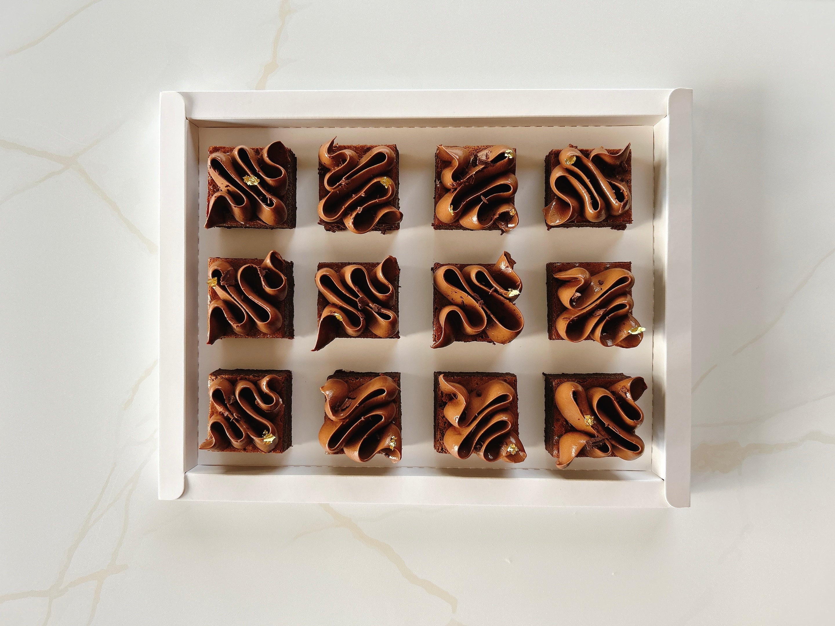 Row of french chocolate fondant cake in a white box on a light marble background