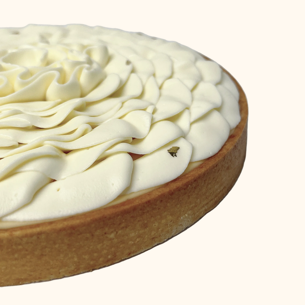 Close-up of a tart maison augustine with white cream topping on a white background