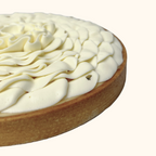 Close-up of a tart maison augustine with white cream topping on a white background