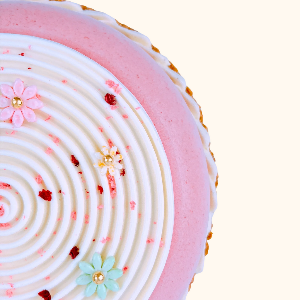 Close-up of a pink and white french cake newvastle with decorative flowers on a light background