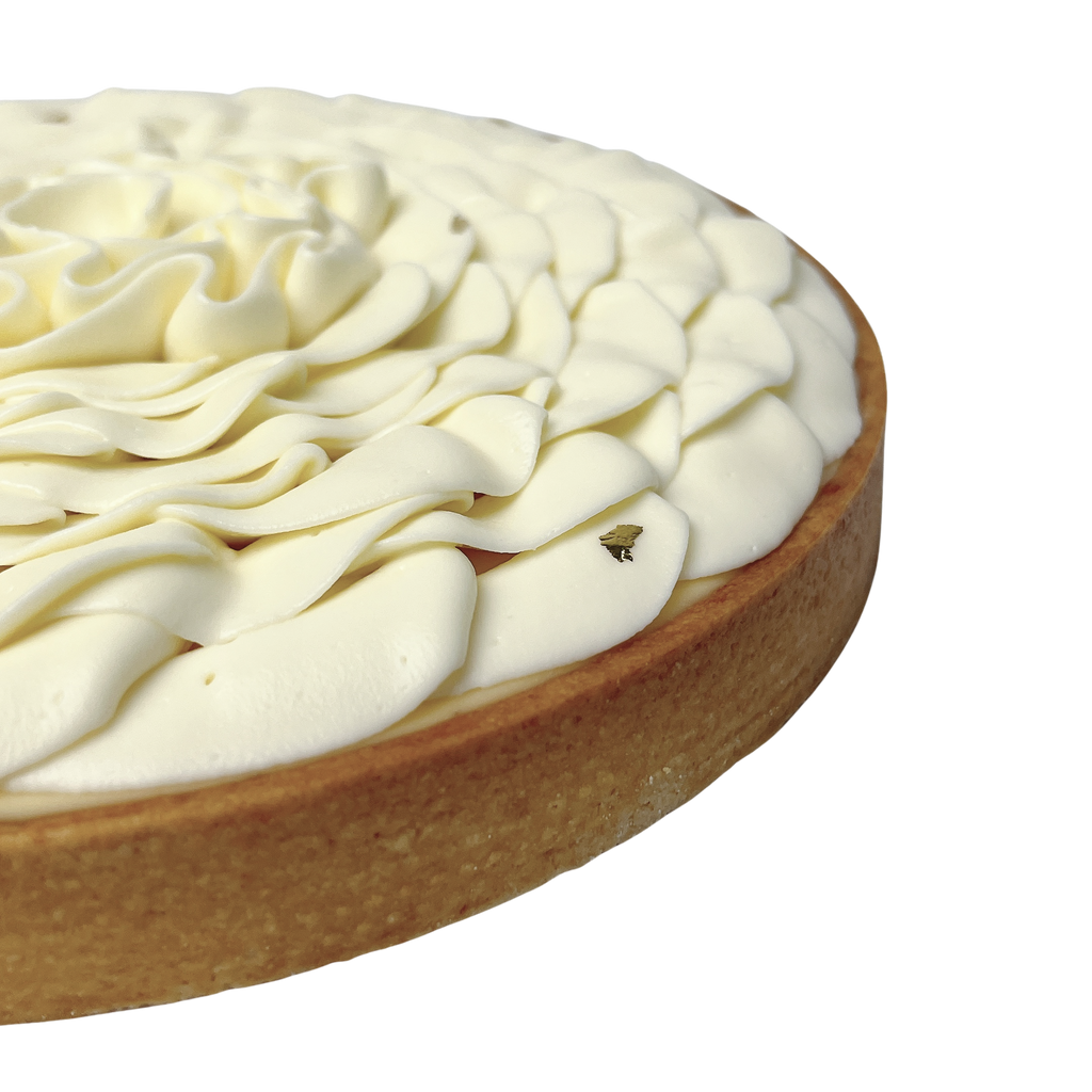 Close-up of a French lemon tart featuring smooth vanilla whipped cream piped into elegant petals and a buttery pastry crust.