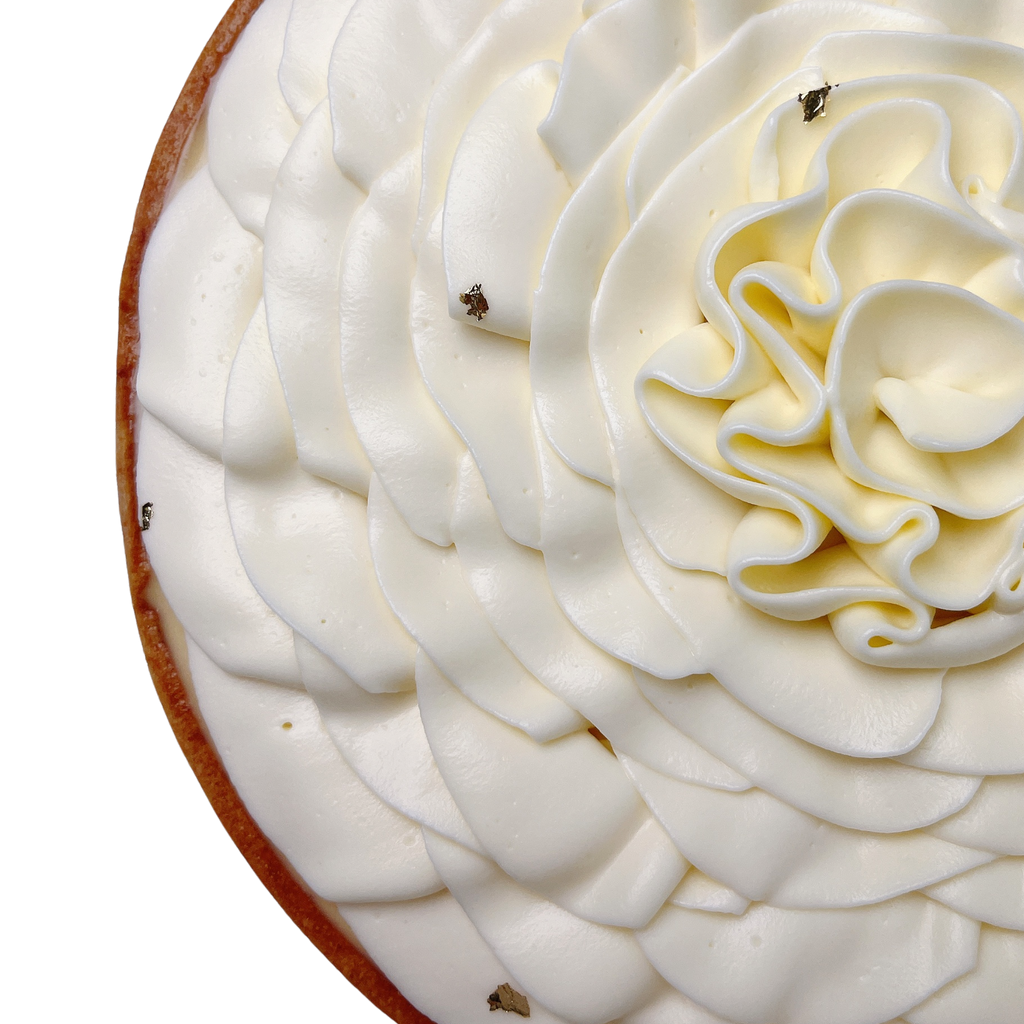 Close-up of a French lemon tart featuring smooth vanilla whipped cream piped into elegant petals and a buttery pastry crust.