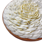 Angled close-up of a handcrafted French lemon tart topped with vanilla whipped cream flower and edible gold leaf.